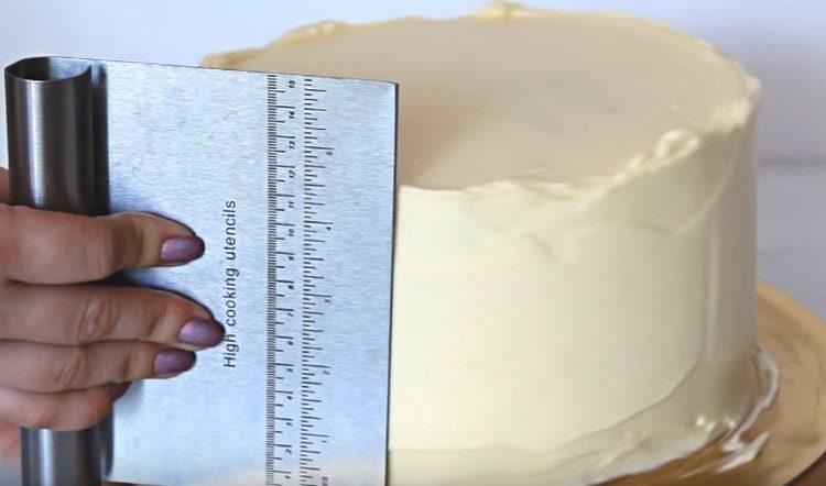 Le gâteau trempé est à nouveau recouvert de crème, nivelant la surface.