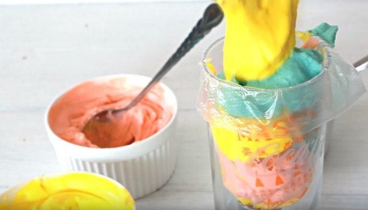 We shift the multi-colored cream into a pastry bag.