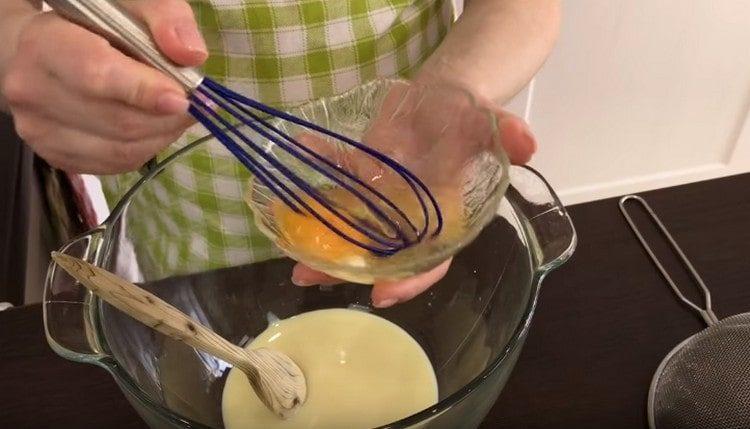 Ulijte kondenzirano mlijeko u posudu za tijesto, dodajte tučeno jaje.