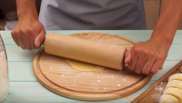 We roll out each portion of the dough with a rolling pin into a cake.