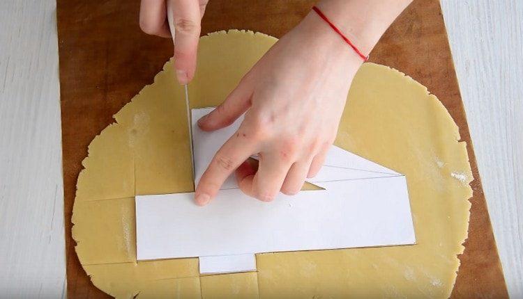 À l'aide d'un morceau de papier, nous découpons des figures dans la pâte.