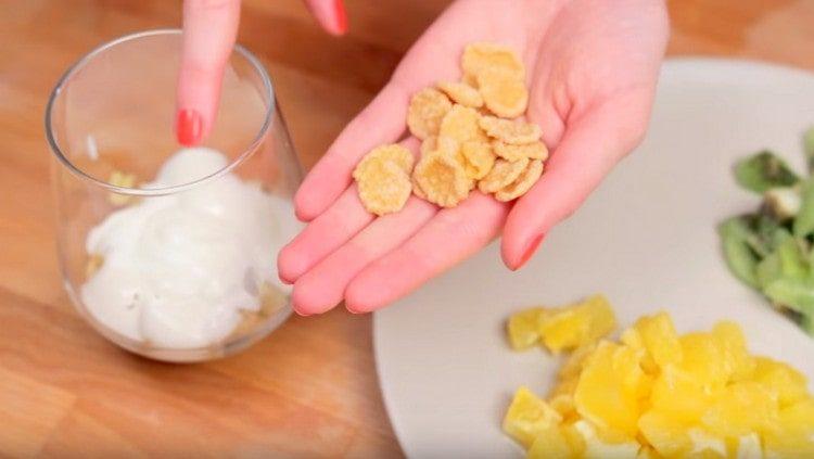 saupoudrer des flocons de maïs sur le yaourt.