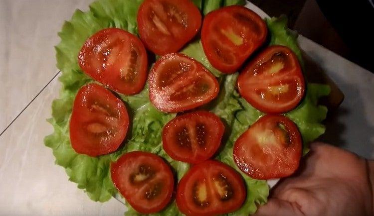 Nous coupons les tomates en cercles et les étalons sur des feuilles de laitue.