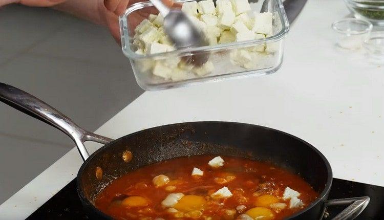 Vi slår ægene i tomatmassen og tilsætter fetaosten.