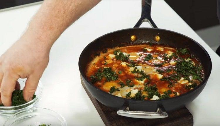 Au moment de servir la shakshuka, préparée selon cette recette, généralement saupoudrée d'herbes hachées.