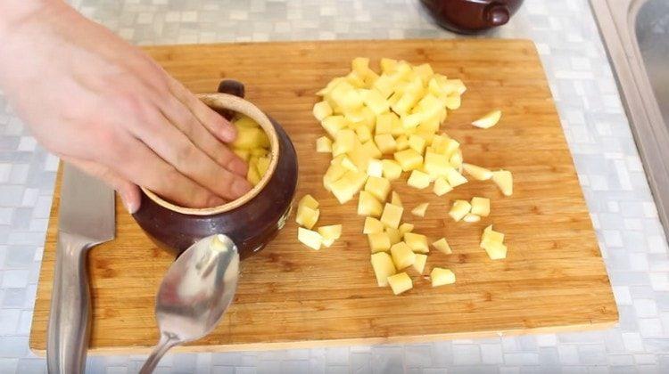 Corte las papas en cubitos y póngalas en macetas encima de la carne.