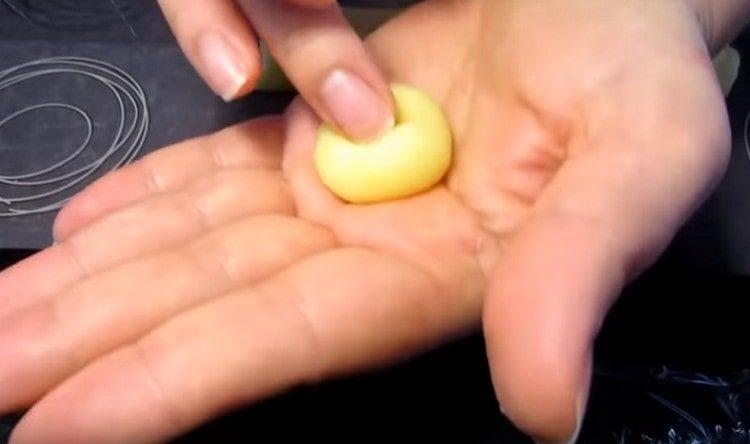 Enrollamos cada pedazo de masa de papa en una bola y hacemos un receso con un dedo.
