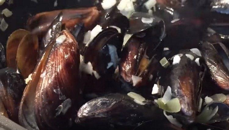 Ponemos los mejillones en una sartén a la cebolla con ajo.