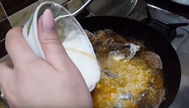 Verser le mélange de crème sure dans la casserole, mélanger et laisser mijoter le plat.