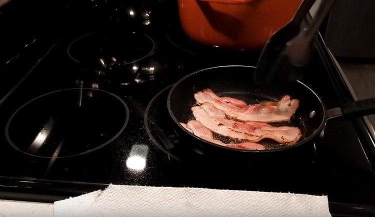 Fry the bacon in a frying pan until golden brown.