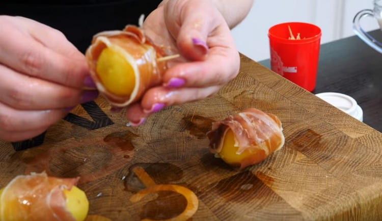 We fasten the potatoes with bacon with the help of toothpicks.
