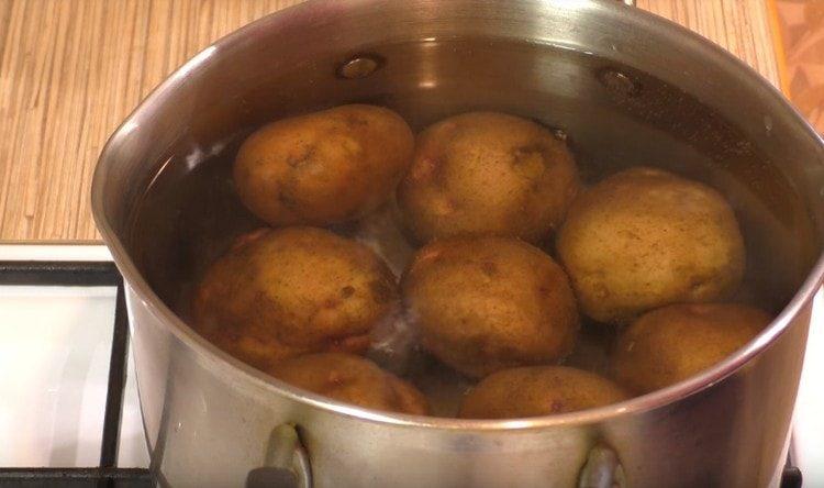First, boil the jacket potatoes in their skins until half ready.