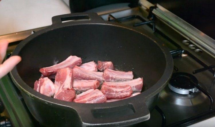 En el aceite caliente, sumerja las costillas de cerdo.
