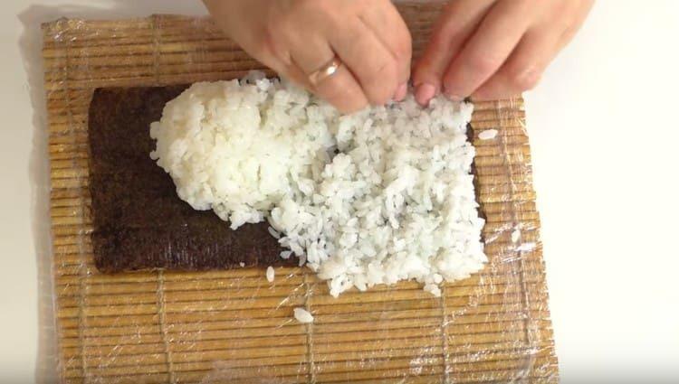 ponga el arroz en una hoja de nori y distribuya uniformemente.