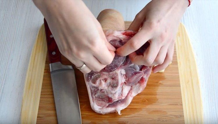 Insert the cloves of garlic into the cuts in the shank.