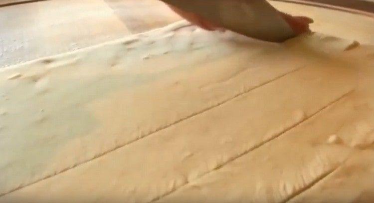 The dough layer is cut into narrow strips.