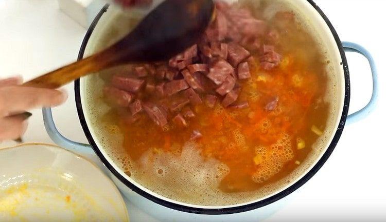 Nous répandons des saucisses dans une casserole avec de la soupe.