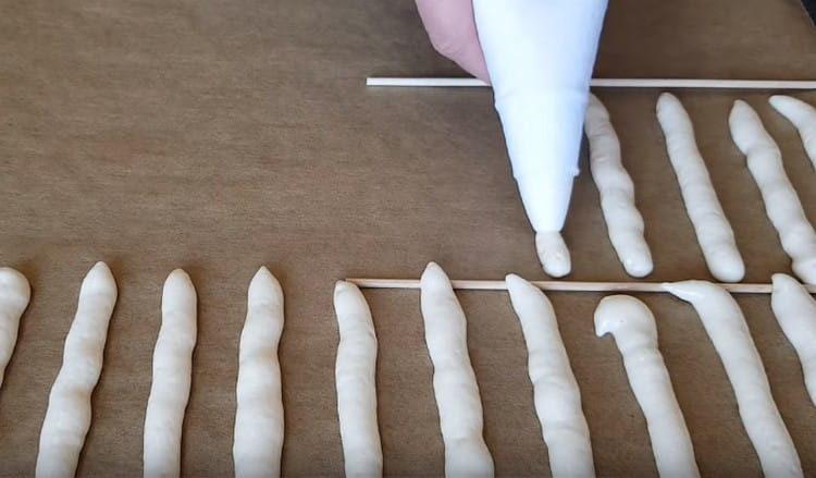 Using a pastry bag, we plant small fingers on a baking sheet covered with parchment.