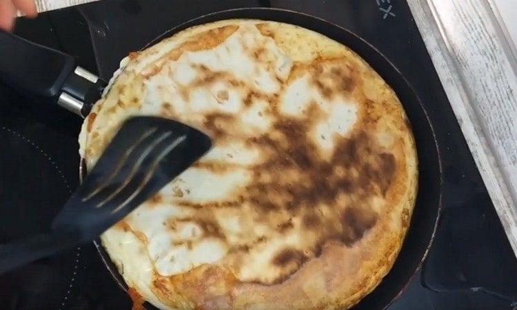 Gently turn the pita bread with fried eggs on the other side.